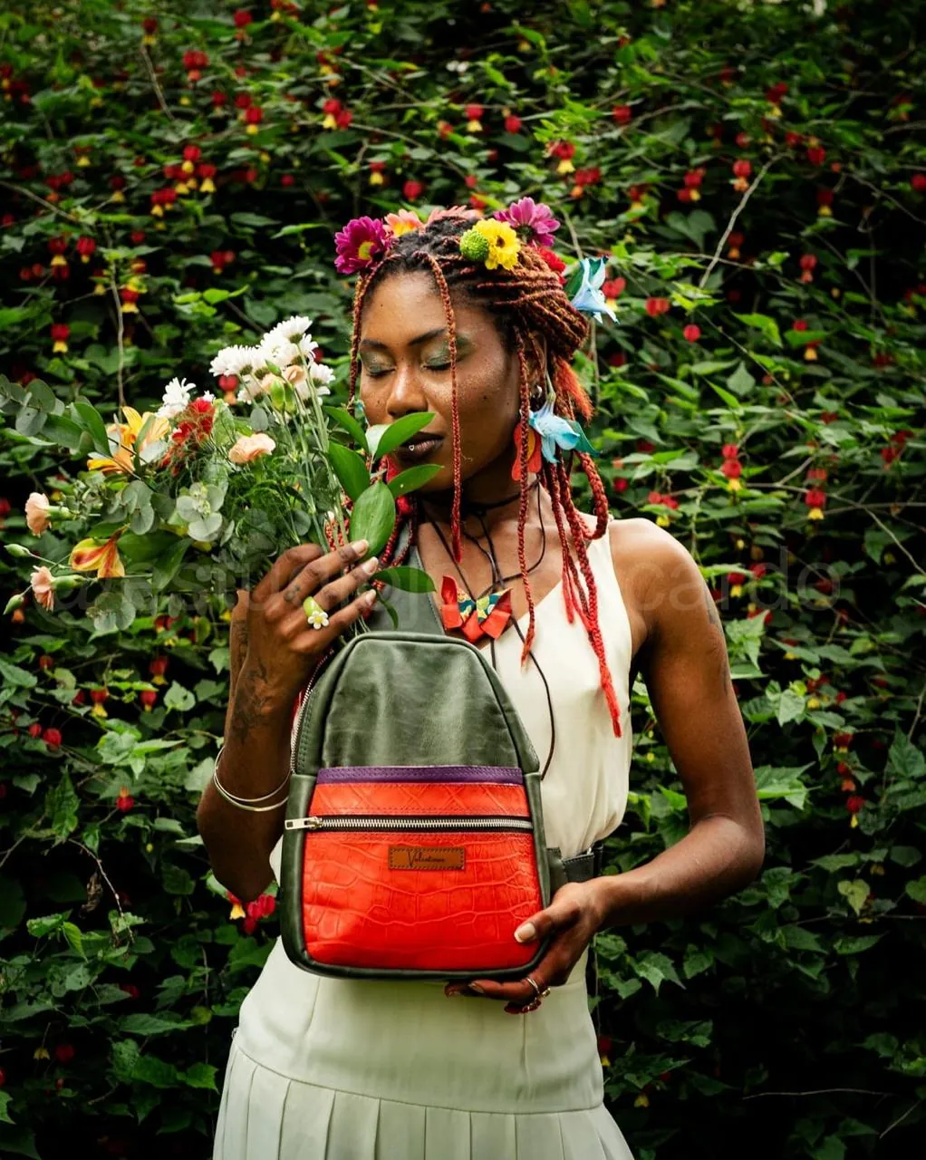 Mulher com flores no cabelo segurando mochila colorida